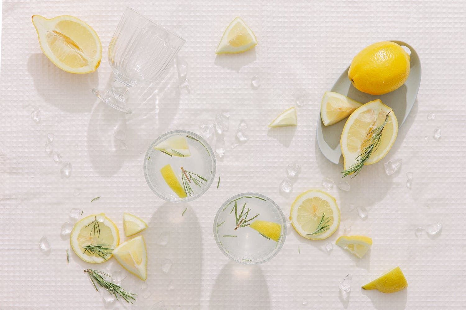 lemon water with slices lemon and lemons around it